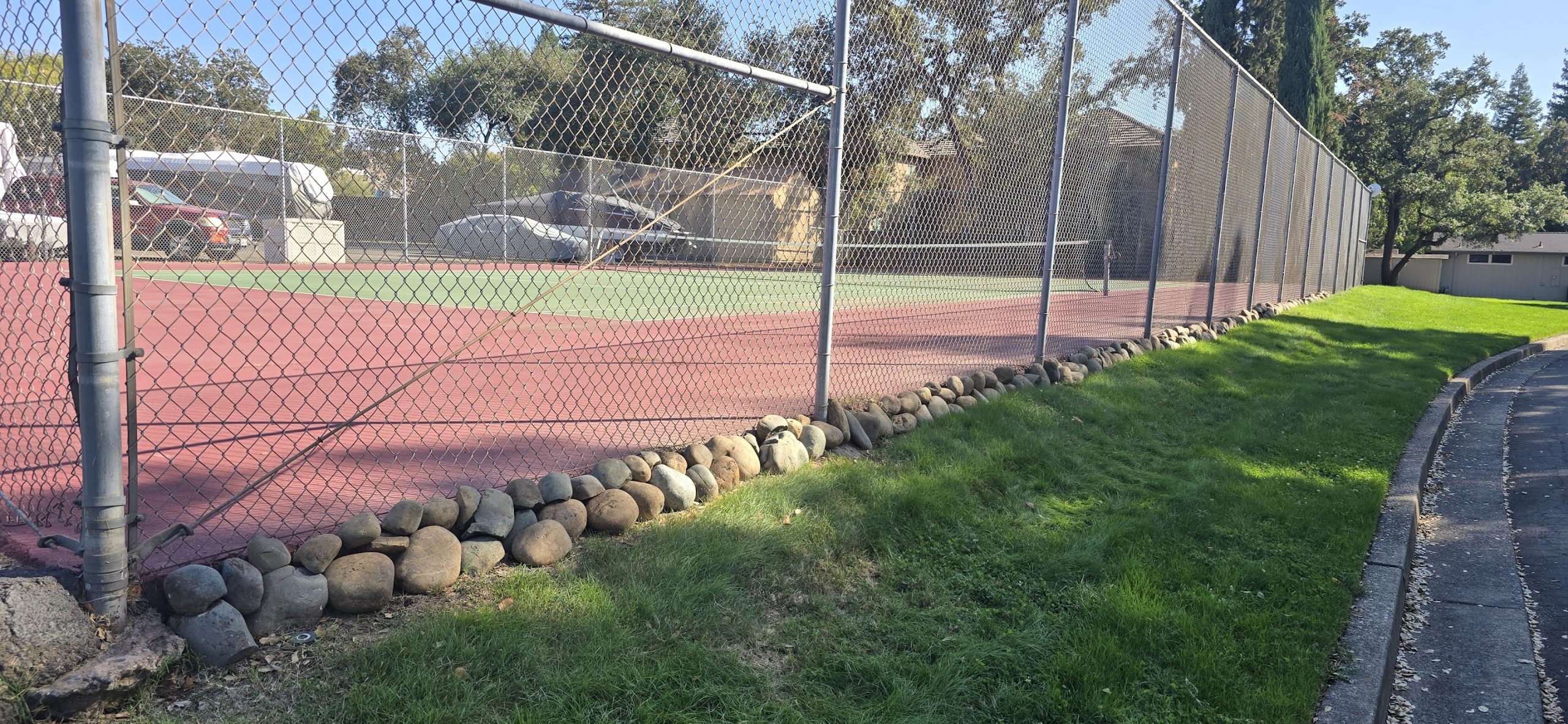 Closer view of rock border placed along tennis court fence base